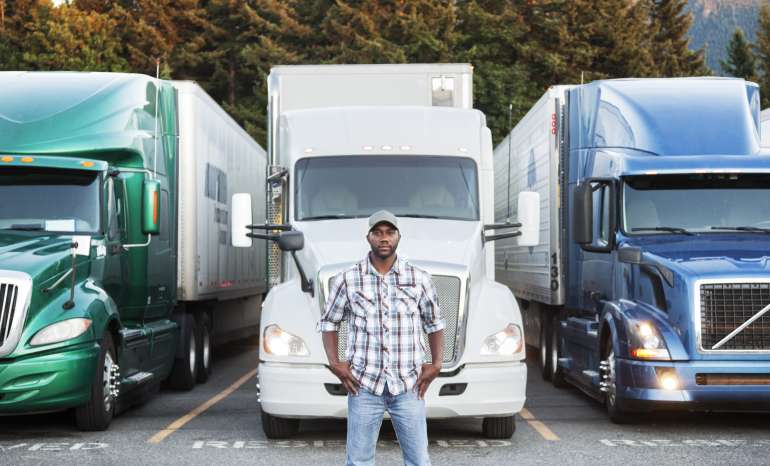 Black Man Truck Driver Near His Truck Parked In A Parking Lot At A Truck Stop
